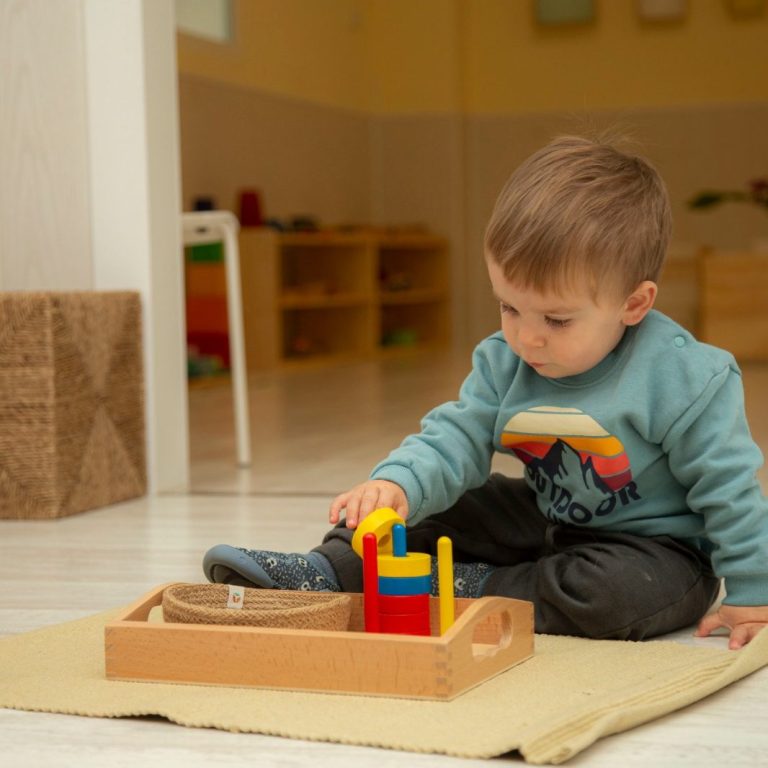 Niño pequeño jugando con bloques de madera Niño pequeño jugando con bloques de madera en un ambiente colorido y acogedor.